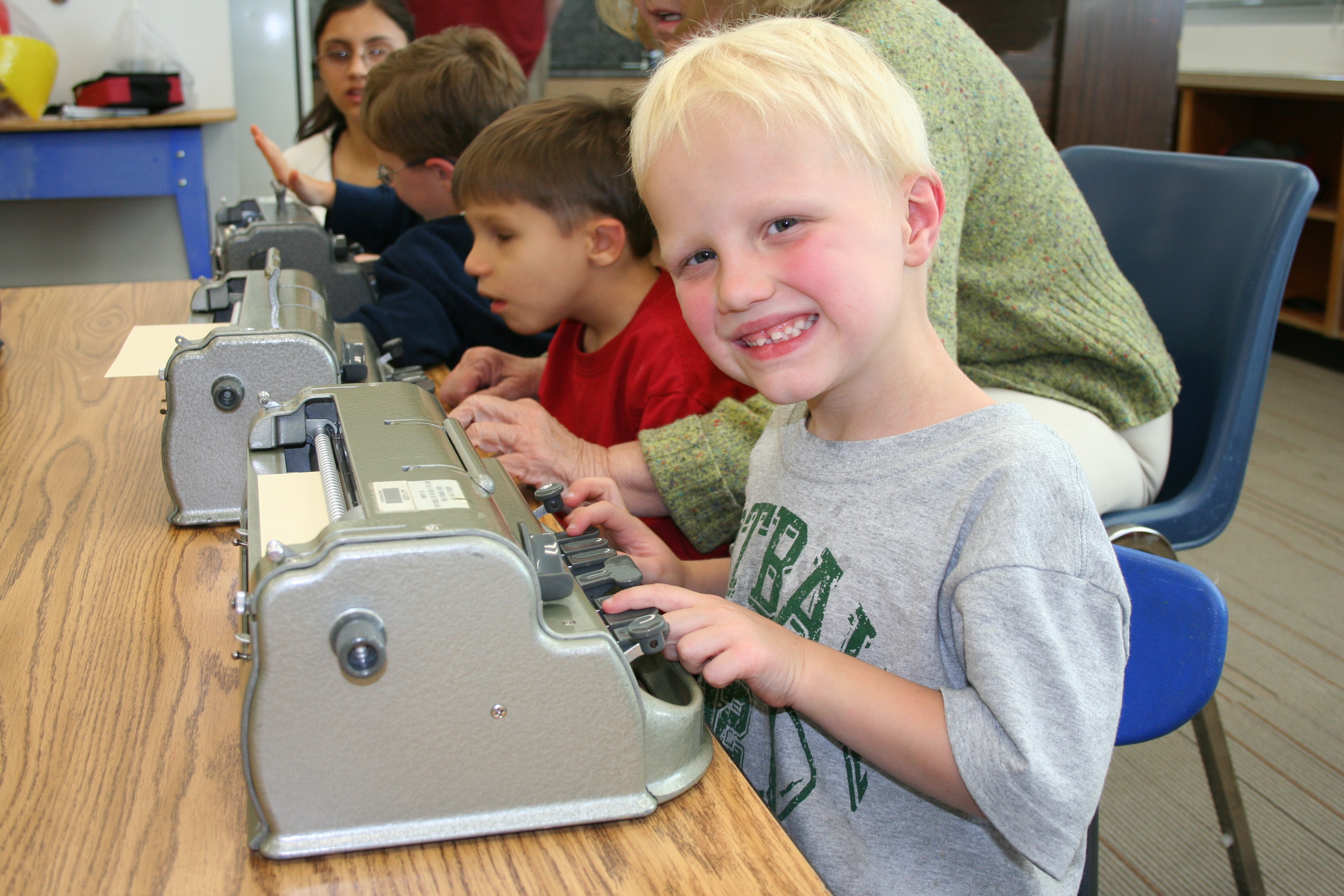 Riley Phelps of the Utah BELL session smiles next to his Braillewriter.